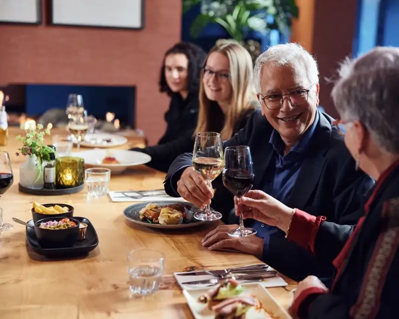 Anstoßende Menschen am Tisch