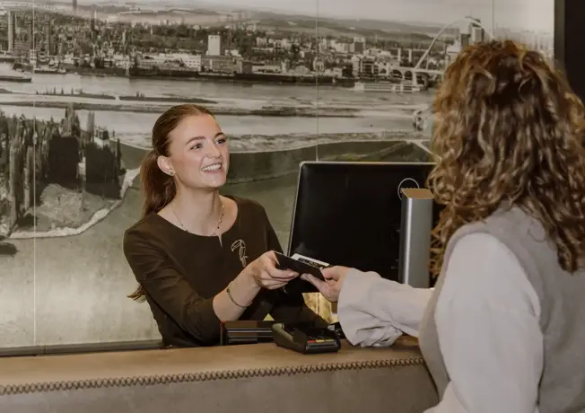 Vater mit zwei Kindern steht an der Rezeption