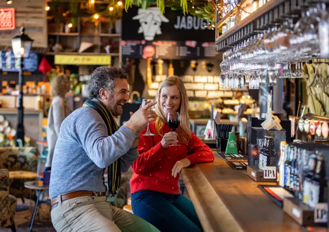 Stel drinks wine at a bar
