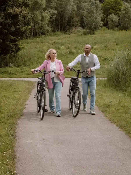Ehepaar geht mit Fahrrad in der Hand spazieren