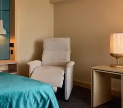Comfortabele fauteuil met bijzettafel in de zithoek van een hotelkamer