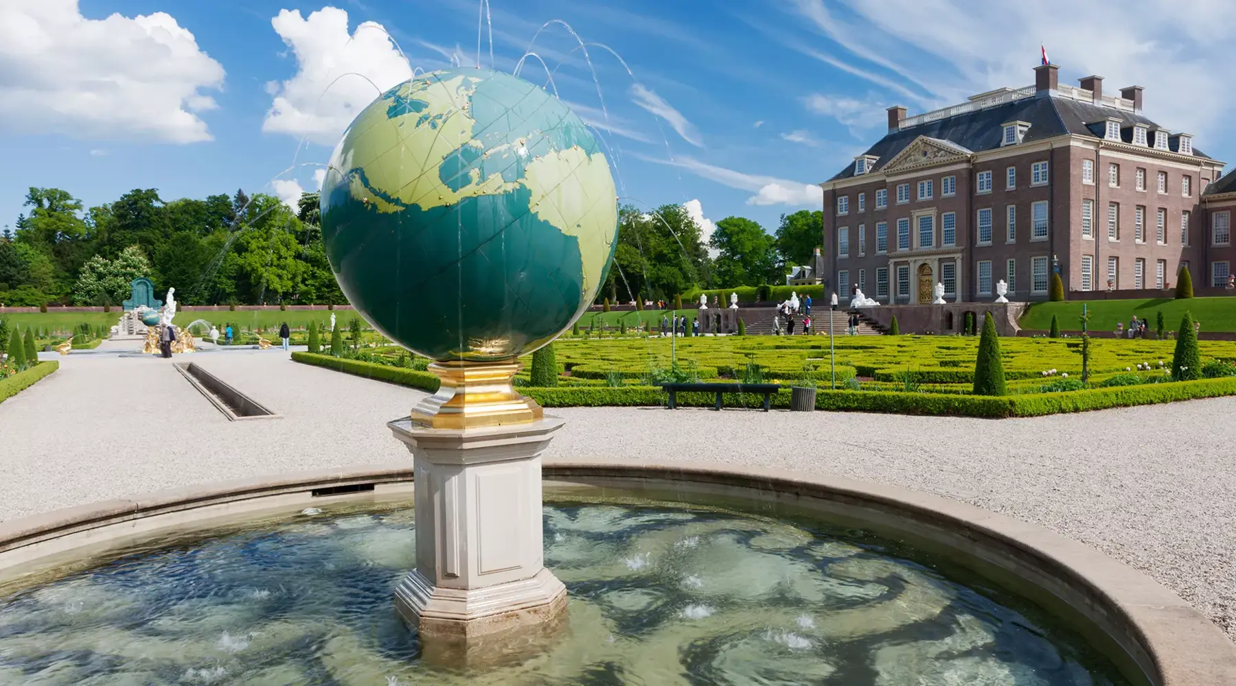 Achterzijde van Paleis het Loo met de tuinen en een fontein met wereldbol