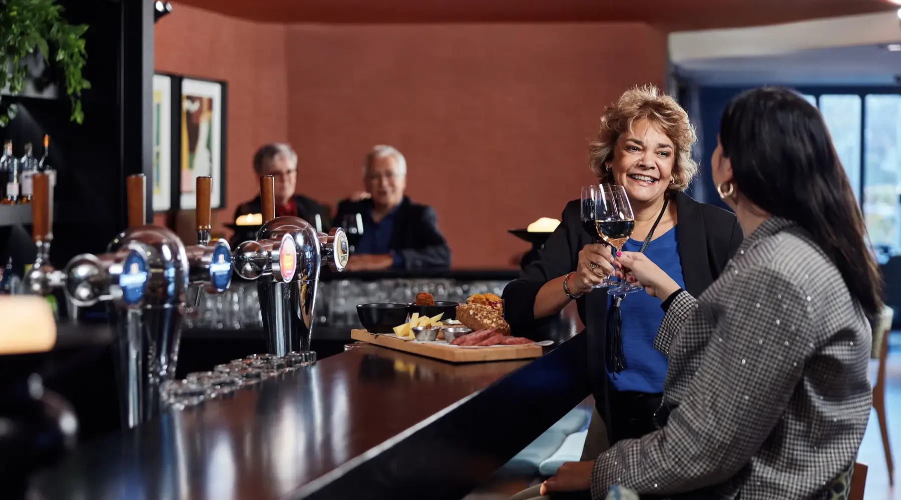 Two women toast at the bar