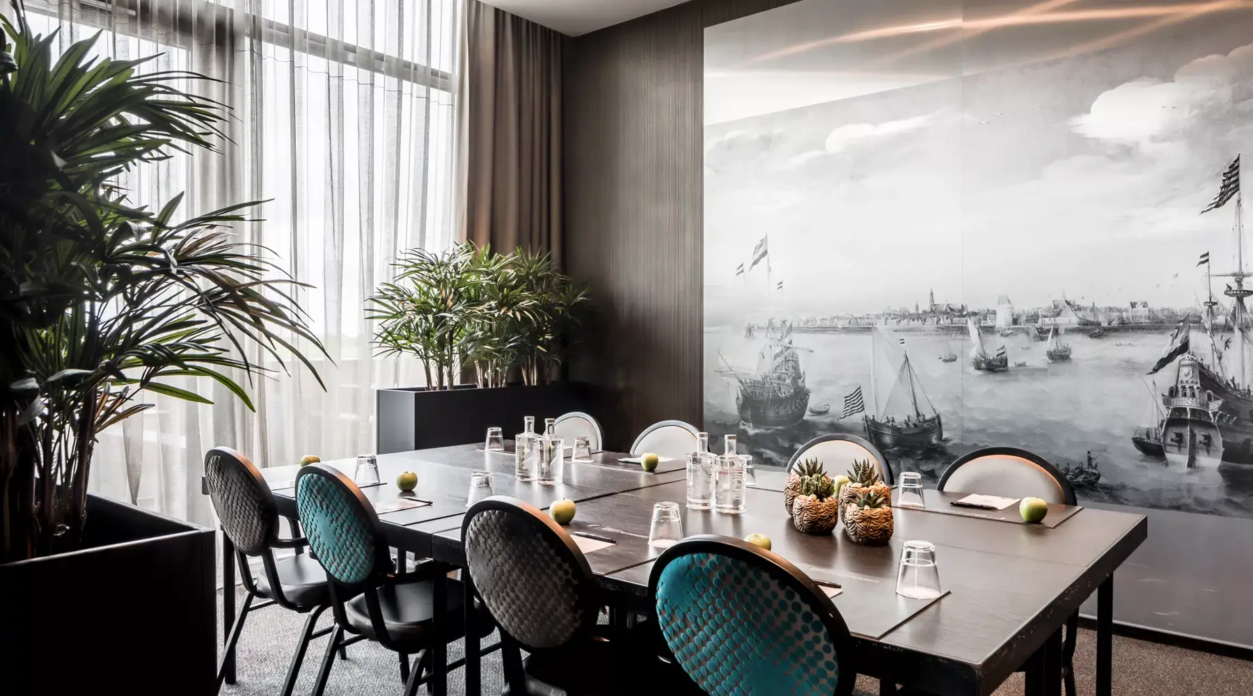 Salle de réunion dans l'hôtel Hoorn. Table sombre avec des chaises vertes et noires. Sur le mur, une peinture murale en noir et blanc avec de vieux navires.