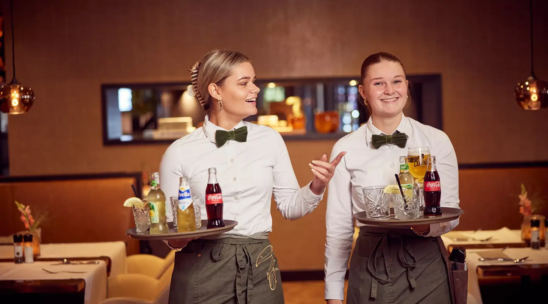 Two waitresses with drinks on trays.