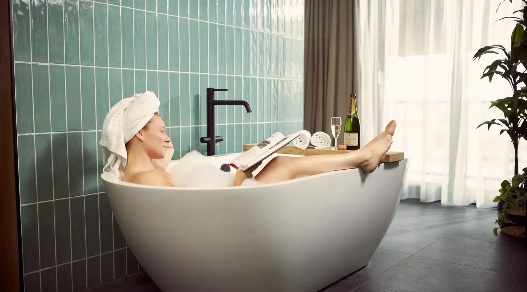 Vrouw geniet met een drankje in de wellness van Hotel Breukelen