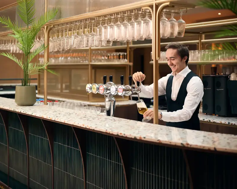 barman die een biertje tapt bij de bar