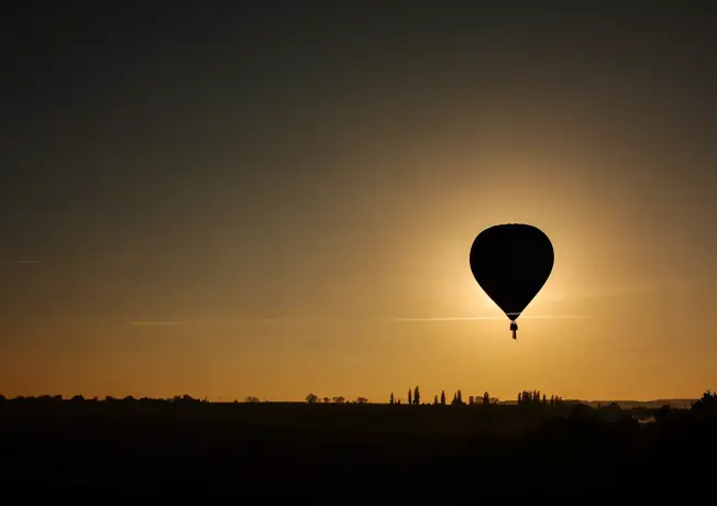 Silhouette eines Heißluftballons vor der untergehenden Sonne.