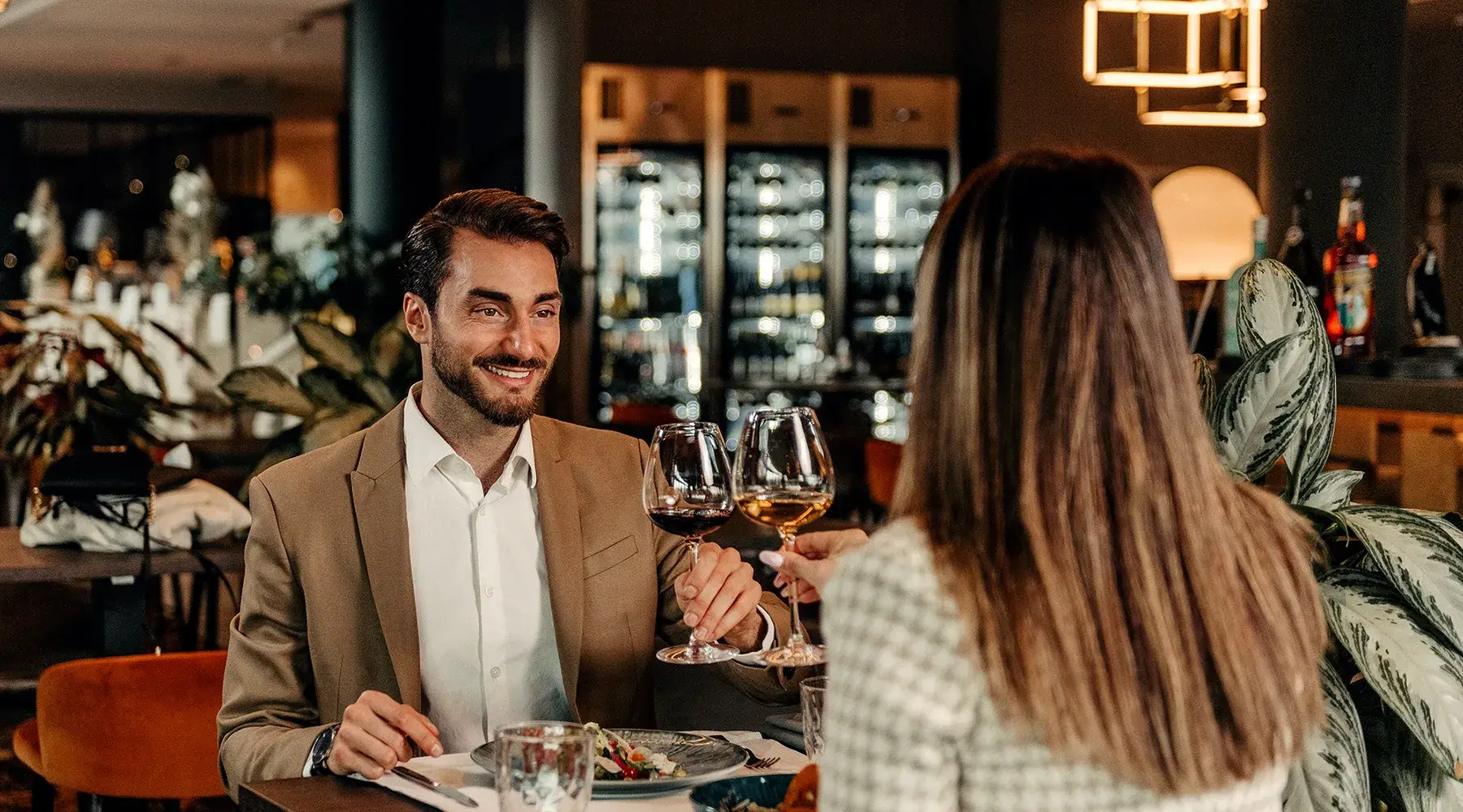 Mann und Frau stoßen beim Abendessen in einem Van der Valk Restaurant in Belgien mit Wein an.