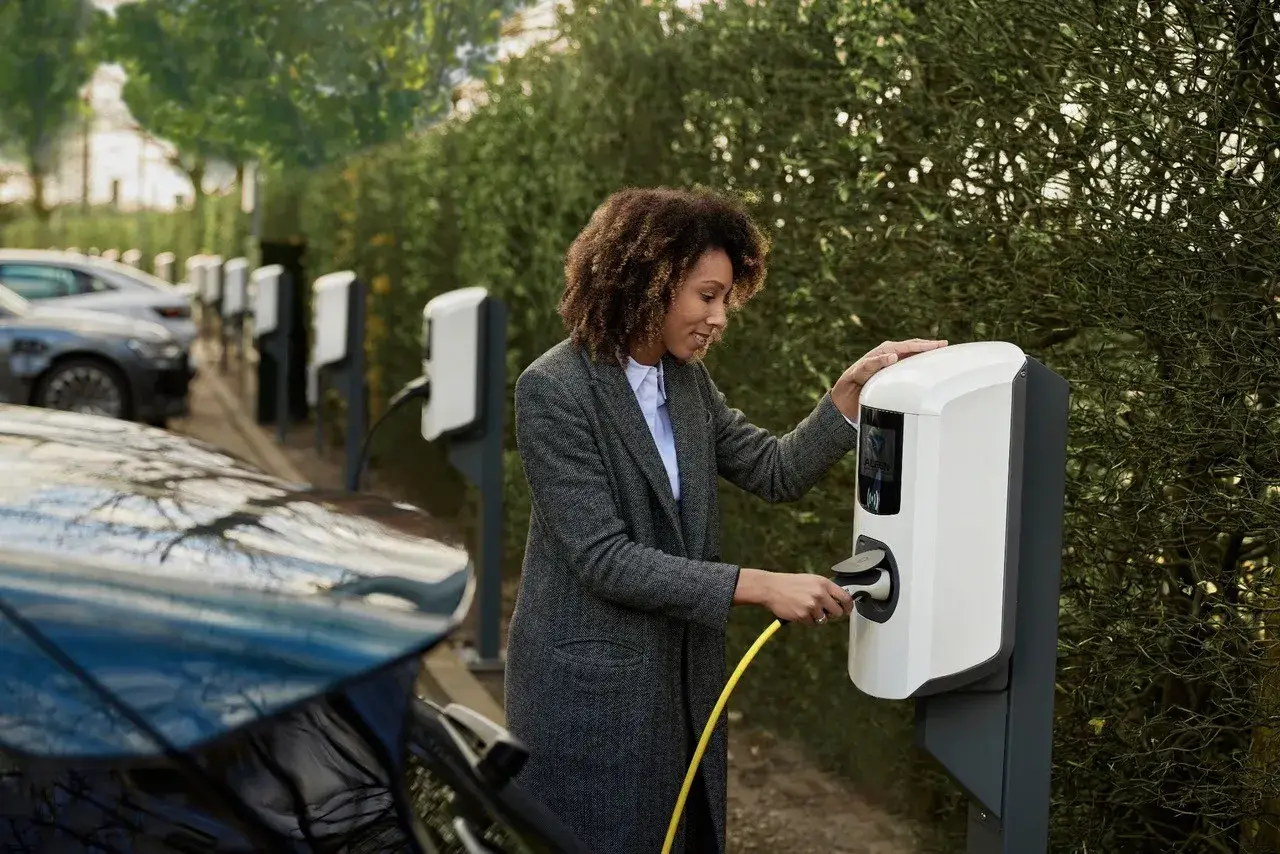 Frau lädt ihr Auto elektrisch auf.