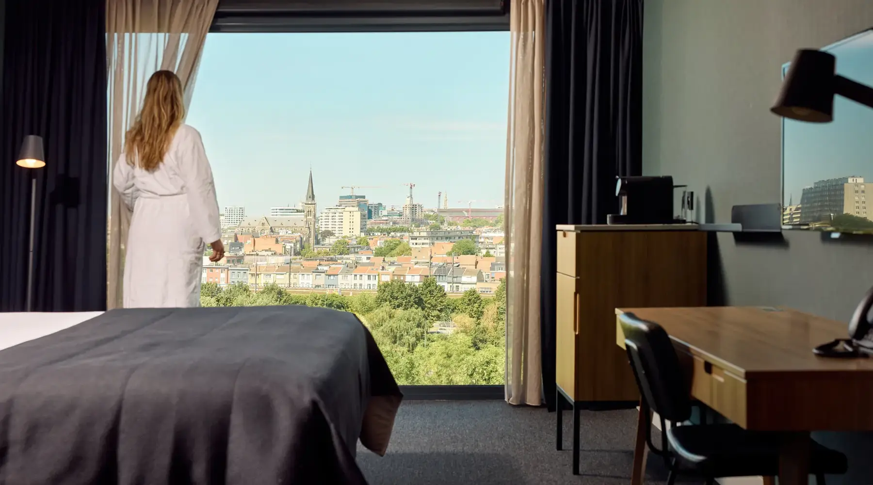 Kamer in hotel Antwerpen. bed met 2 stoelen aan klein tafeltje.1 stoel aan het bureau voor de TV. 