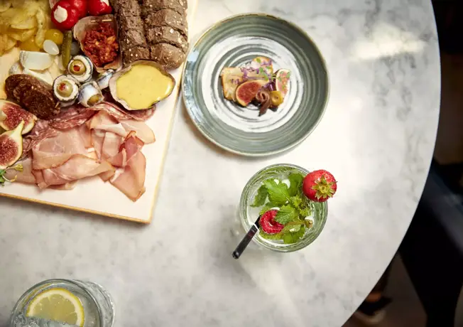 Snack platter halfway on the table and drinks