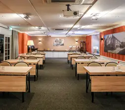 Vue d'ensemble des aménagements scolaires confortables dans le hall, avec les installations pour le café et les boissons en arrière-plan.