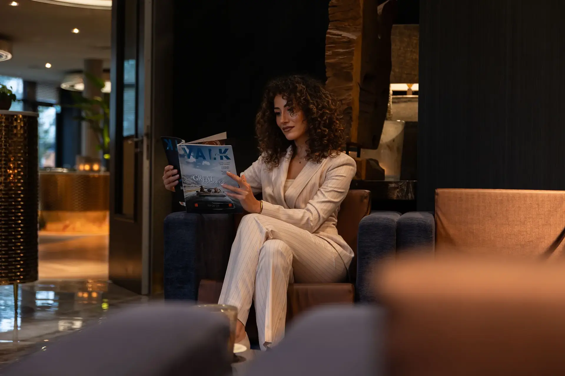 Vrouw in pak leest het Valk Magazin in de lobby van een hotel.